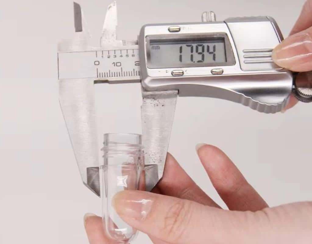 An Engineer Using A Digital Caliper And A Go/No-Go Gauge To Inspect A Batch Of Incoming Pet Preforms.