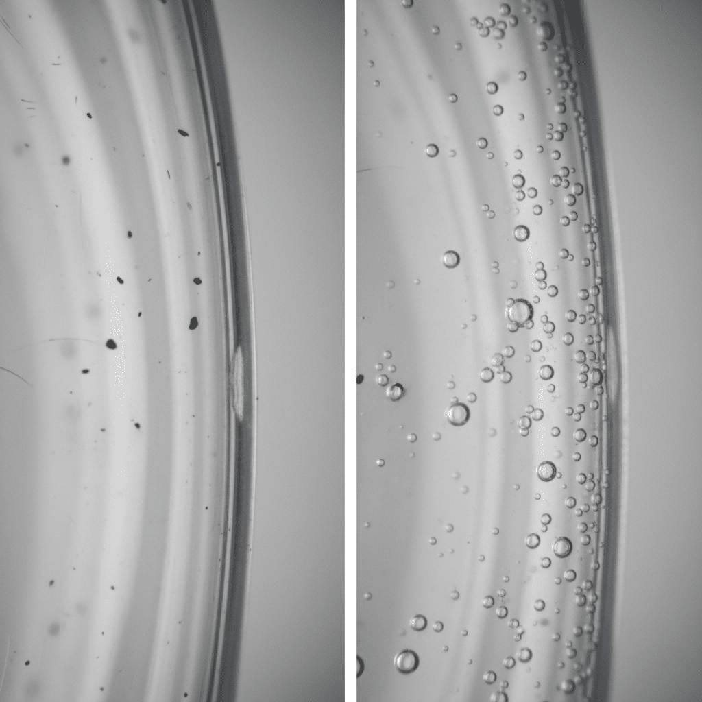 A Close-Up Of A Clear Pet Bottle Wall Showing Embedded Black Specks, And Another Bottle With Visible Air Bubbles In The Plastic.